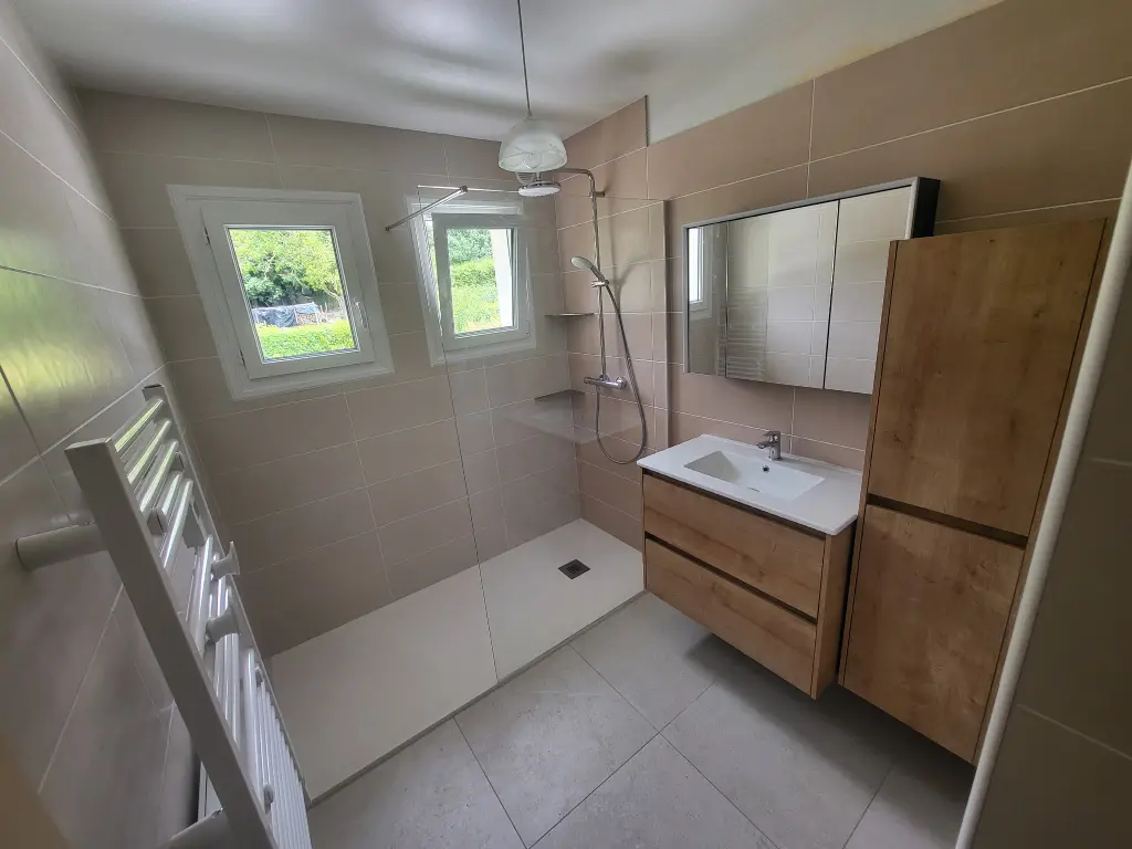 Salle de bain rénovée avec douche ouverte et nouveaux équipements sanitaires
